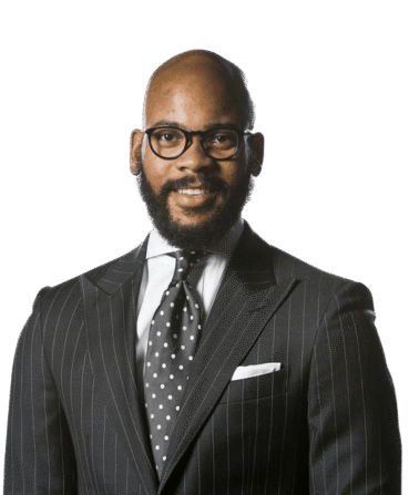 Professional studio portrait of Dr. Corrie Shull, a man with a beard and glasses, smiling slightly against a light gray background.